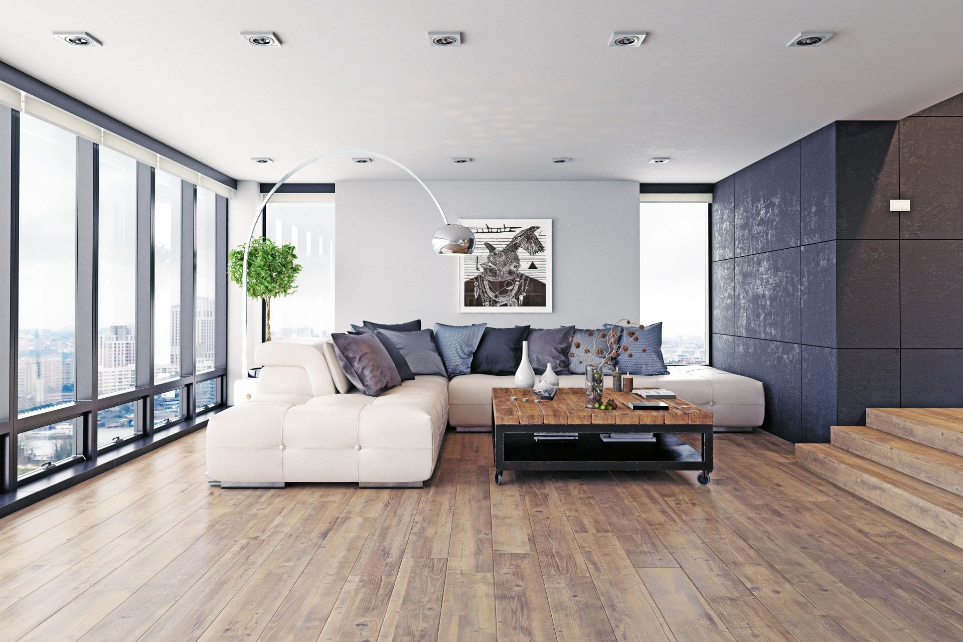 Modern living room with large windows, a white sectional sofa, laminate flooring, various throw pillows, a wooden coffee table, floor lamp, potted plant, and a city view in the background.
