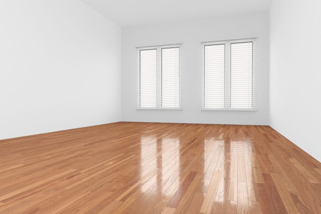 Abel Pro Blog: Empty room with polished wooden floors, white walls, and two windows with closed white blinds letting in natural light.
