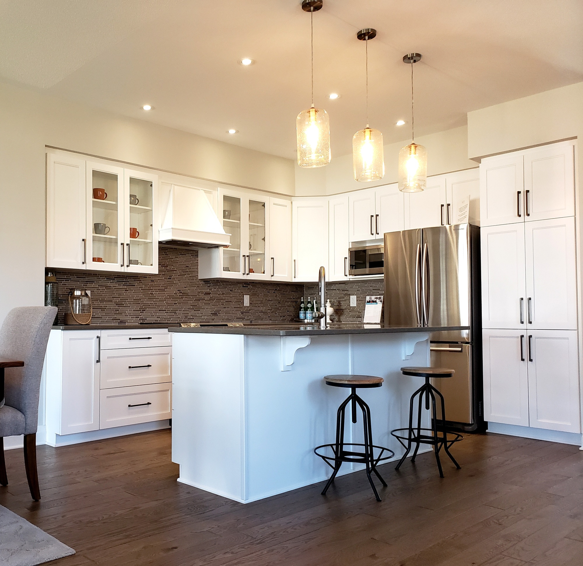 Full view of a renovated kitchen plan with new cupboards, mosaic tiled backsplash, and hardwood floor. Contact Abel Pro to make your renovation dreams a reality.