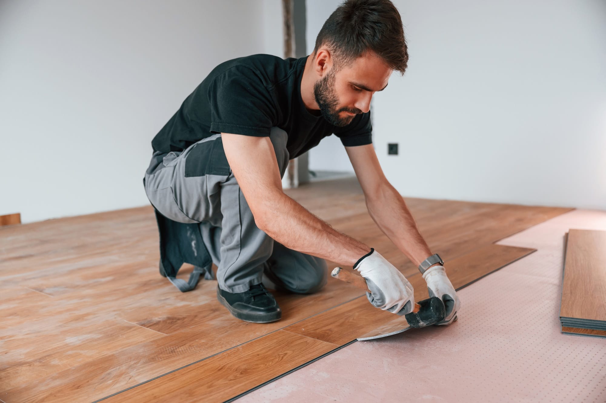 Using the rubber hammer. Man is installing new laminated wooden floor