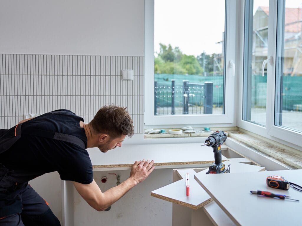 Man measuring flooring in a well-lit room with tools, emphasizing precision for accurate installation.