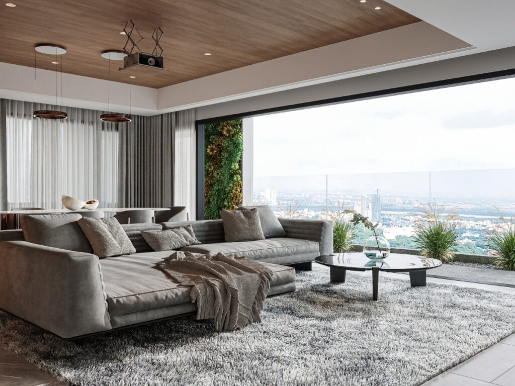 Modern living room with grey sectional sofa, shaggy rug, and glass coffee table, featuring large windows with a city view and balcony with plants&mdash;enhanced by benefits of soundproof flooring for a peaceful retreat.