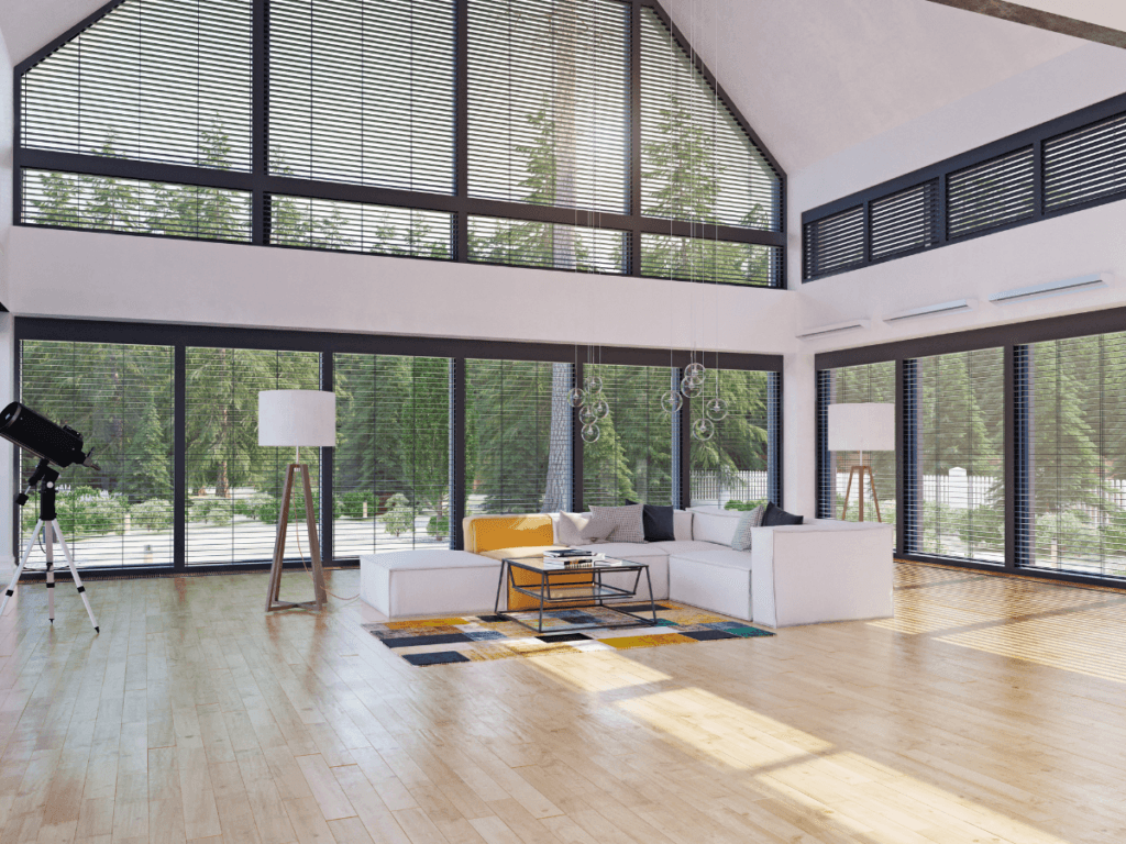 A spacious modern living room with large windows, light sunroom flooring, a white sectional sofa, a colorful rug, and a telescope facing outside.