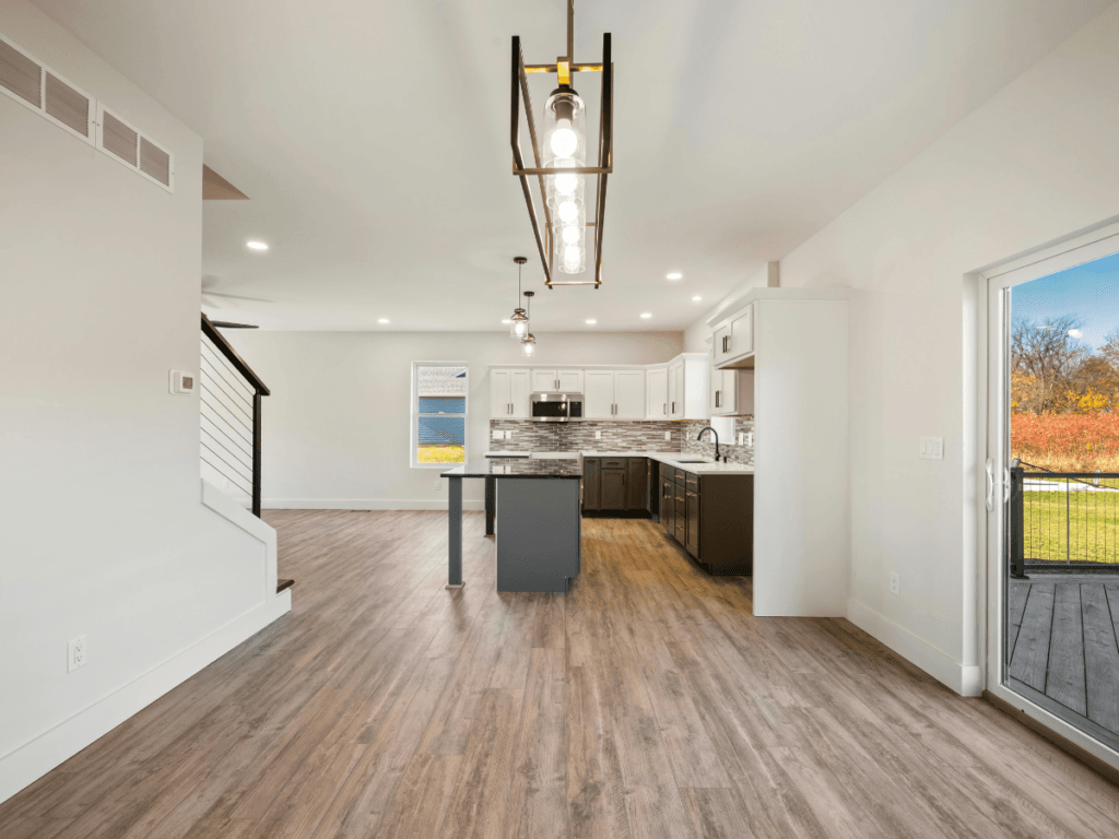 Bright modern kitchen with white cabinets, stainless steel appliances, island, Marietta allergy flooring, and a sliding glass door to a patio with a grassy view.